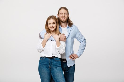 Portrait of cheerful young couple standing and hugging each other on isolated white background.