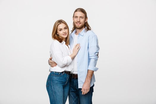 Portrait of cheerful young couple standing and hugging each other on isolated white background.