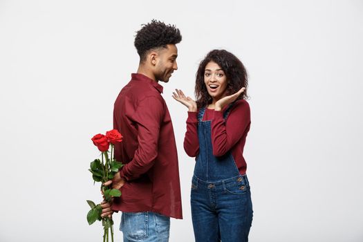 Beautiful elegant couple is hugging and smiling, on gray background. Girl is holding roses.