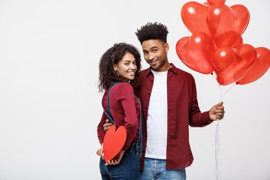 Young attactive African American couple holding heart balloon and paper