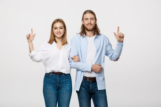 Portrait young happy couple love smiling embracing point finger to empty copy space, man and woman smile looking up, isolated over white background.