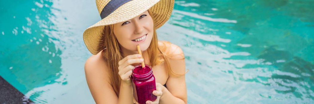 BANNER, LONG FORMAT Young woman drinking Dragon fruit smoothies on the background of the pool. Fruit smoothie - healthy eating concept. Close up of detox smoothie with Dragon fruit.
