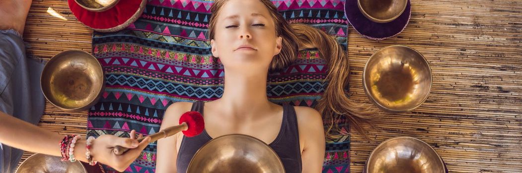 BANNER, LONG FORMAT Nepal Buddha copper singing bowl at spa salon. Young beautiful woman doing massage therapy singing bowls in the Spa against a waterfall. Sound therapy, recreation, meditation, healthy lifestyle and body care concept.