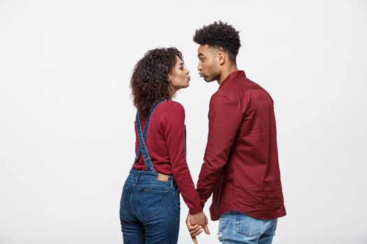 Close-up of African American young couple kissing over white background studio.