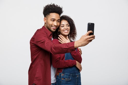 Young attractive African American Couple Pose For selfie pose with smart phone.