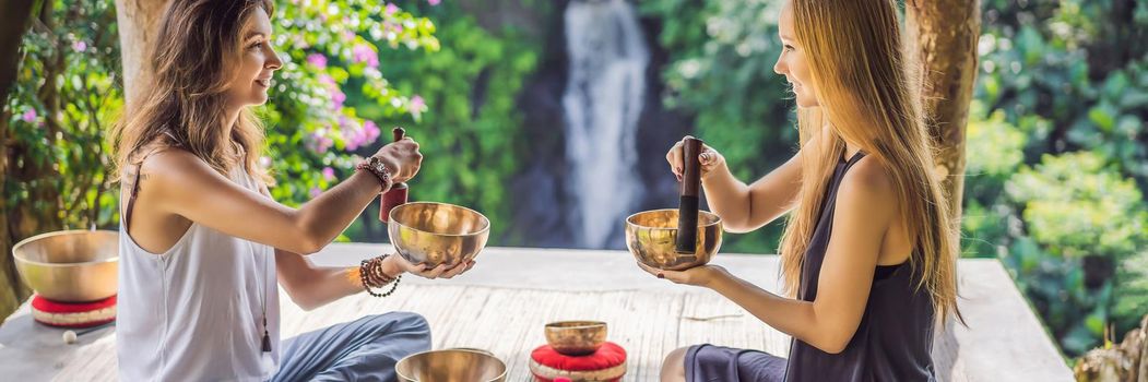 BANNER, LONG FORMAT Nepal Buddha copper singing bowl at spa salon. Young beautiful woman doing massage therapy singing bowls in the Spa against a waterfall. Sound therapy, recreation, meditation, healthy lifestyle and body care concept.