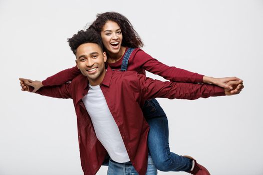 Close-up young african american couple riding back and playing like plane