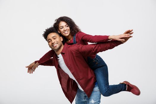 Close-up young african american couple riding back and playing like plane