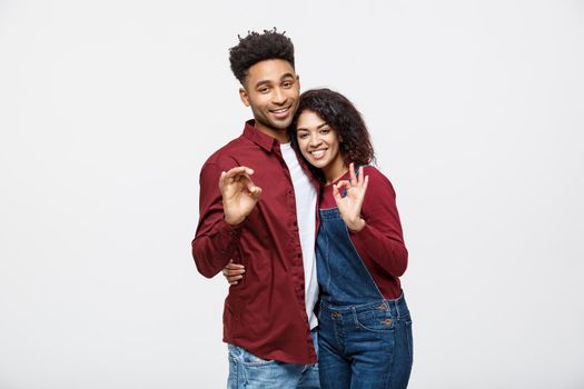 Portrait of a cheerful young african couple standing together and showing ok gesture isolated over white background.