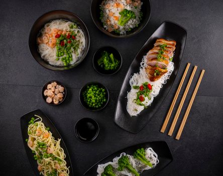 Various dishes of Asian cuisine with different types noodles and rice with shrimp, vegetables and black sesame