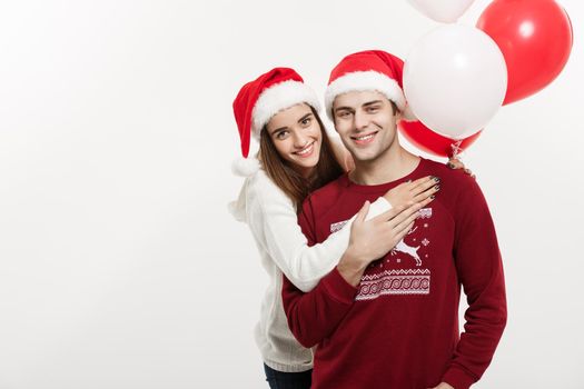 Christmas Concept - Young girlfriend holding balloon is hugging and playing with her boyfriend doing a surprise on Christmas.