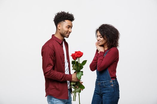 Beautiful elegant couple is hugging and smiling, on gray background. Girl is holding roses.