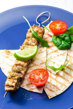 herbal meat skewer  with pita bread, tomatoes and lime