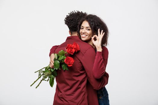 Couple Concept - Young african american couple huging each other and holding romantic red rose