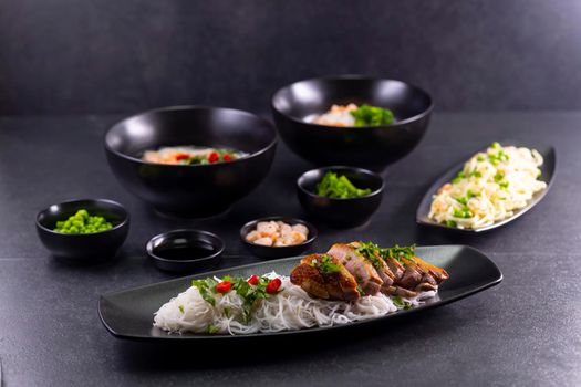 Various dishes of Asian cuisine with different types noodles and rice with shrimp, vegetables and black sesame
