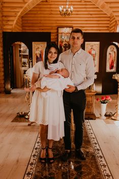 Letychiv, Ukraine - 10.15.2020: rite of sacrament of epiphany baby in church. Newborn baby boy in the arms of godparents in church.
