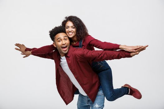 Close-up young african american couple riding back and playing like plane