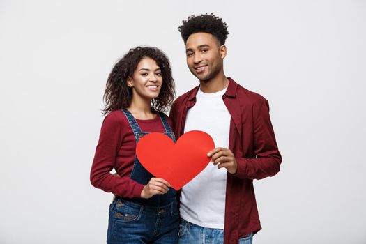 Young happy African American couple in love holding red paper heart