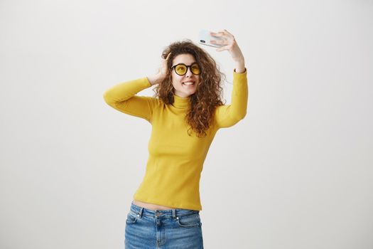 Charming stylish woman making selfie photo on smartphone isolated on a white background