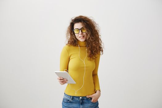 beautiful woman in headphones listening music and using digital tablet isolated on grey