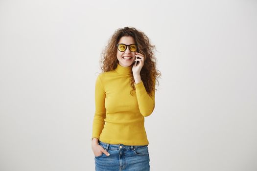 Cheerful young woman talking on mobile phone isolated on gray background