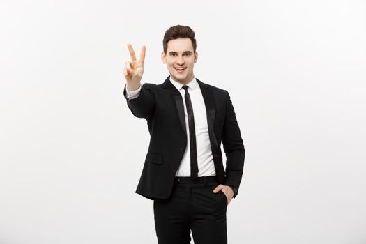 Happy businessman showing two fingers or victory gesture, against grey background. Success in business, job and education concept. Blank copyspace area for advertisiment, slogan or text.