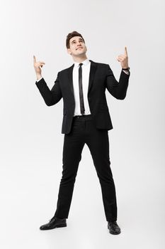 Business Concept: Handsome Man Happy Smile Young Handsome Guy in smart suit posing pointing finger over Isolated Grey Background