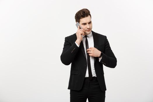 Business Concept: Handsome businessman in suit and speaking on the phone over isolated grey background