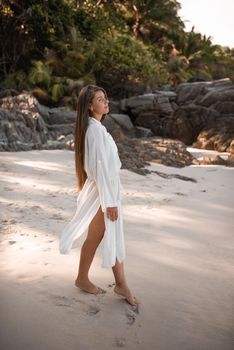 european young tan women have rest and run on white sand beach. long black chestnut hair . white cotton clothes. boho style dress.Thailand. Aquamarine crystal sea