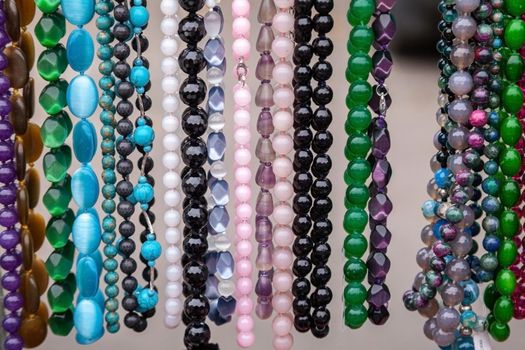 Various colorful beads in the market. Wallpaper background of a colorful necklace made of precious stones and colored beads. Semi-precious jewelry.