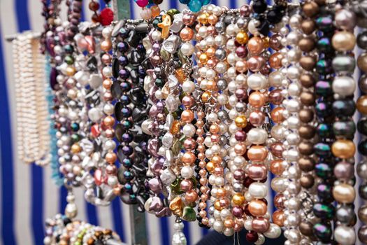 Various colorful beads in the market. Wallpaper background of a colorful necklace made of precious stones and colored beads. Semi-precious jewelry.