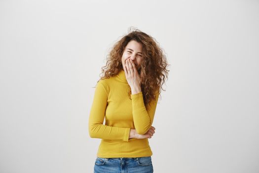 Young girl standing isolated on grey wall playing around looking camera smiling happy close-up.