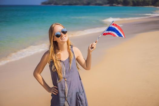 Happy woman having fun at the beach with Thailand flag. Beautiful girl enjoying travel to Asia.