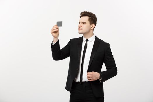 Portrait of a businessman holding a credit card and seriously checking isolated over grey background