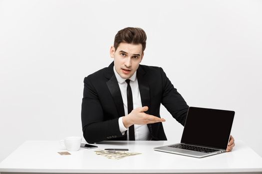 Smiling businessman presenting his laptop computer to the viewer with a blank screen with copy space.