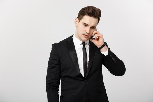 Business Concept: Portrait of young handsome businessman talking on mobile phone with serious and stress expression. Isolated over white background