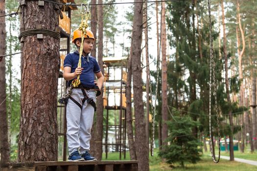 The boy is ready to go on an obstacle in a rope town