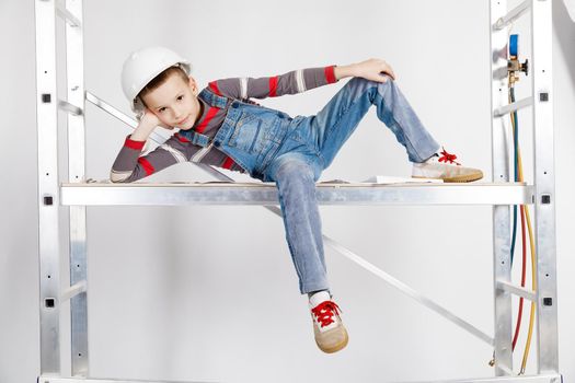 Boy builder in a helmet lying on the scaffolds