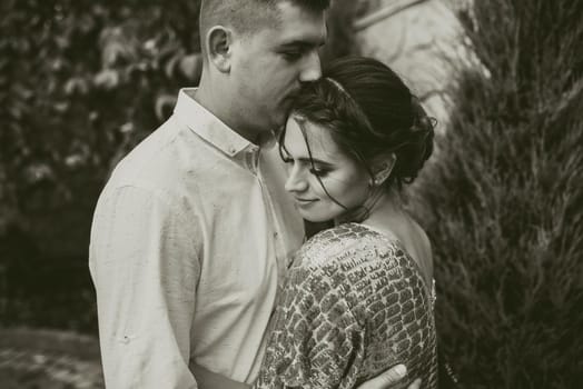 Young couple of lovers man and woman in festive fashionable clothes are hugging. Light casual hairstyle for women with a perm. Summer nature outside background.