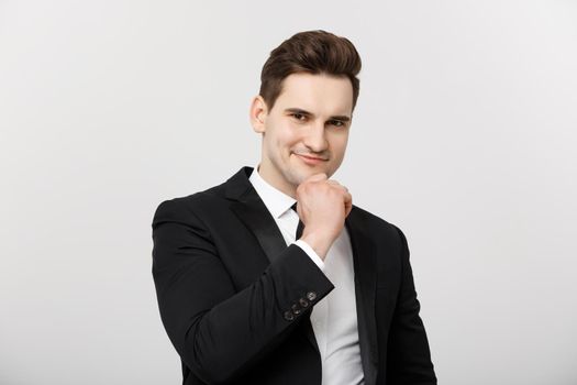 Business Concept: Smiling thoughtful handsome man standing on white isolated background and touching his chin with hand.