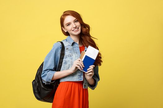 Travel and Lifestyle concept: Full length studio portrait of pretty young student woman holding passport with tickets. Isolated on bright yellow background