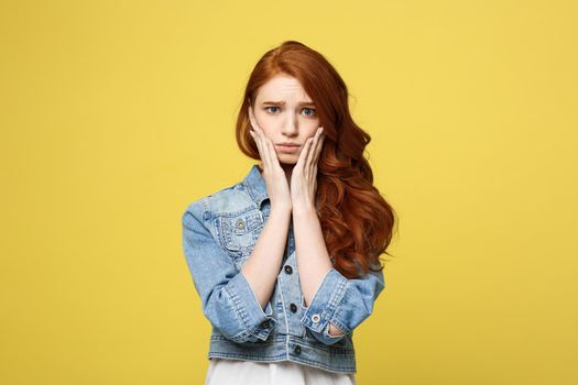 Close up Portrait young beautiful attractive redhair girl worry with something. Golden yellow Background. Copy space