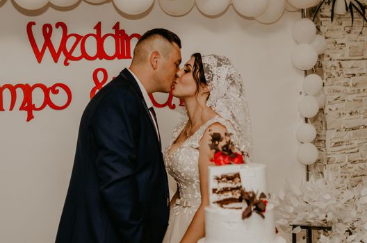 groom and bride at wedding cut their large multi-tiered white cake taste it fed from each other. Slavic Ukrainian Russian traditions