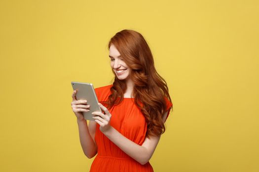 Business Women, Smiling business woman, Business lady, Work concept: Portrait of smiling charming redhead young woman with working on tablet isolated over bright yellow background
