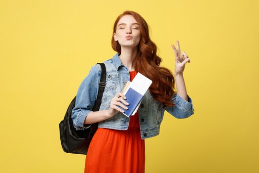 Travel and Lifestyle concept: Full length studio portrait of pretty young student woman holding passport with tickets. Isolated on bright yellow background