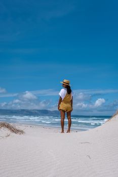 Cape Nature Walker Bay beach near Hermanus Western Cape South Africa. white beach and blue sky with clouds, sand dunes at the beach in South Africa, woman walking at white beach