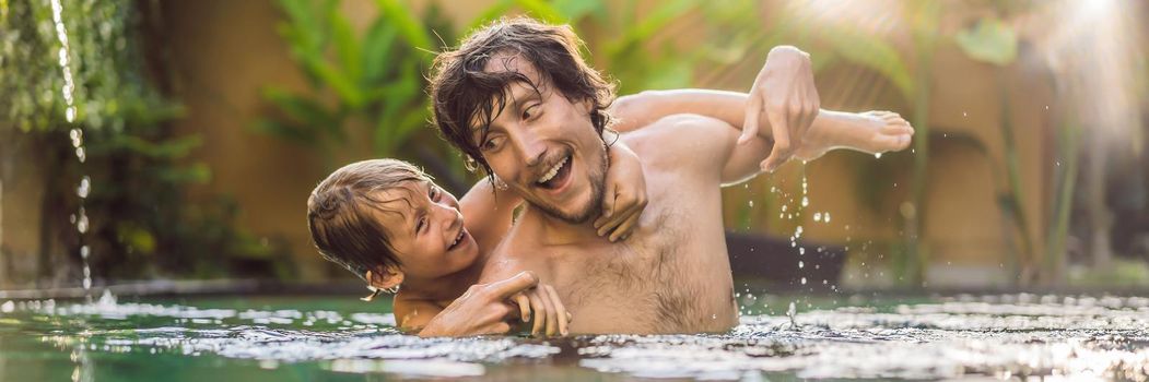 Dad and son have fun in the pool. BANNER, LONG FORMAT