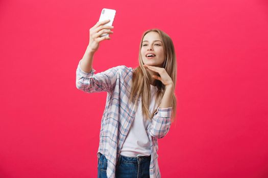 Charming young woman in white hat travel and take selfie on front camera smartphone posing isolated on shine pink background.