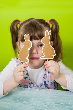 Beautiful girl holds gingerbread cookies in the form of a rabbit. Easter gingerbread cookie