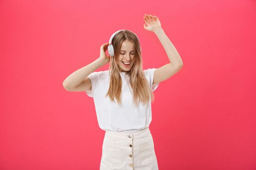 Funny woman with headphones dancing singing and listening to the music from a smart phone isolated on a white background